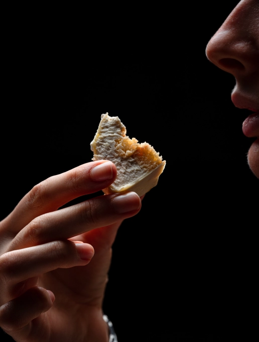 A woman at the ‘Dans le Noir?’ restaurant in Paris, holding a piece of cake close to her mouth