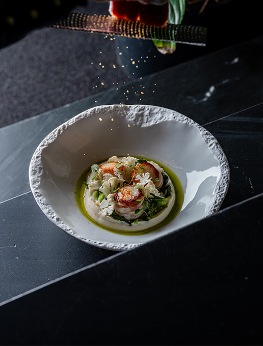 Plato refinado de vieiras con emulsión y verduras crujientes, servido en el restaurante Dans le Noir ?