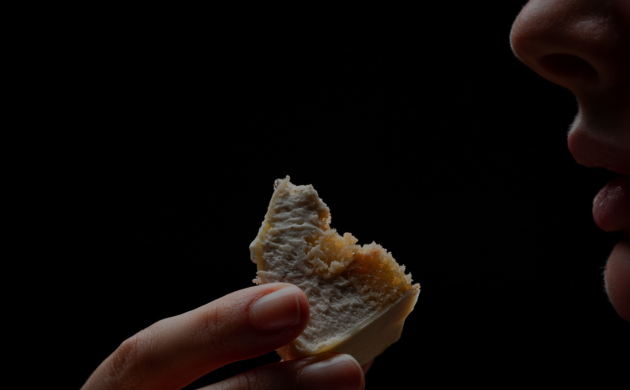 Femme dégustant un morceau de dessert dans l’obscurité lors d’un dîner sensoriel chez Dans le Noir ? Paris